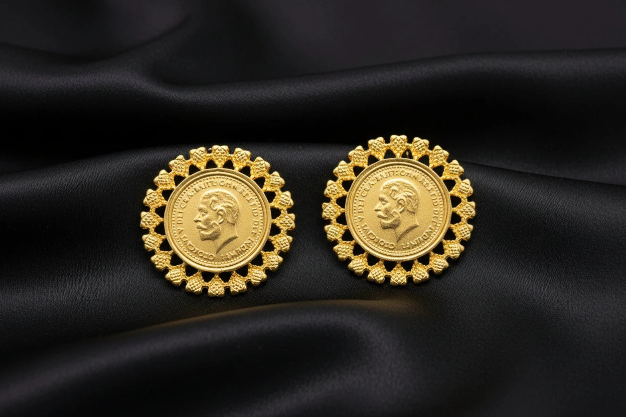 Pair of gold coin earrings with decorative designs on a black background