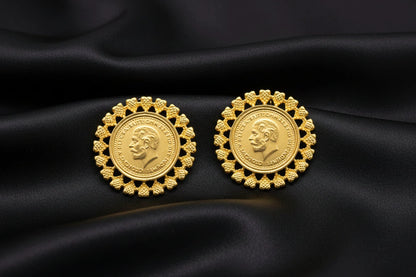 Pair of gold coin earrings with decorative designs on a black background