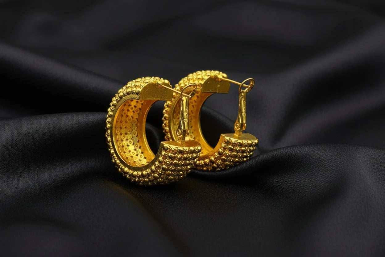 Gold hoop earrings with textured design on a black background