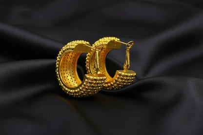 Gold hoop earrings with textured design on a black background