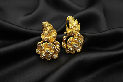 Gold floral  drop earrings with embedded stones on a black background