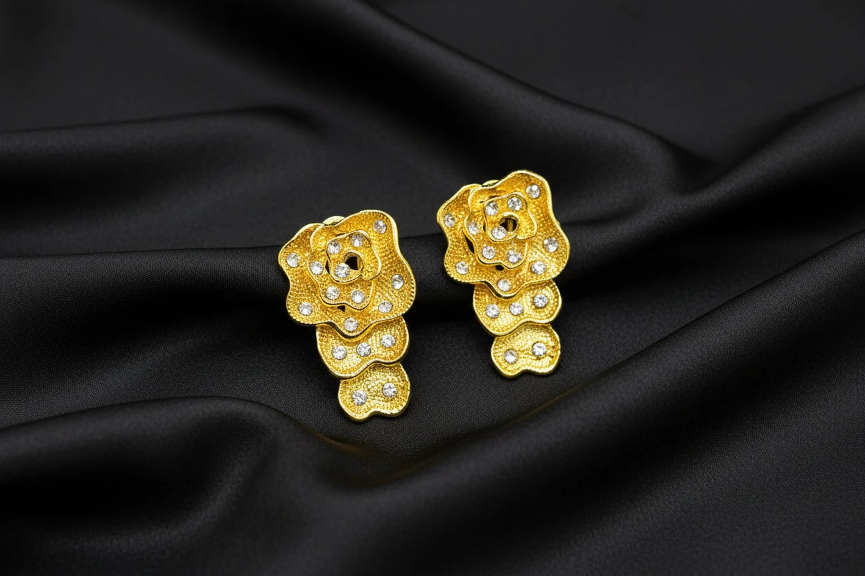 Gold classic floral earrings with rhinestones on a black surface