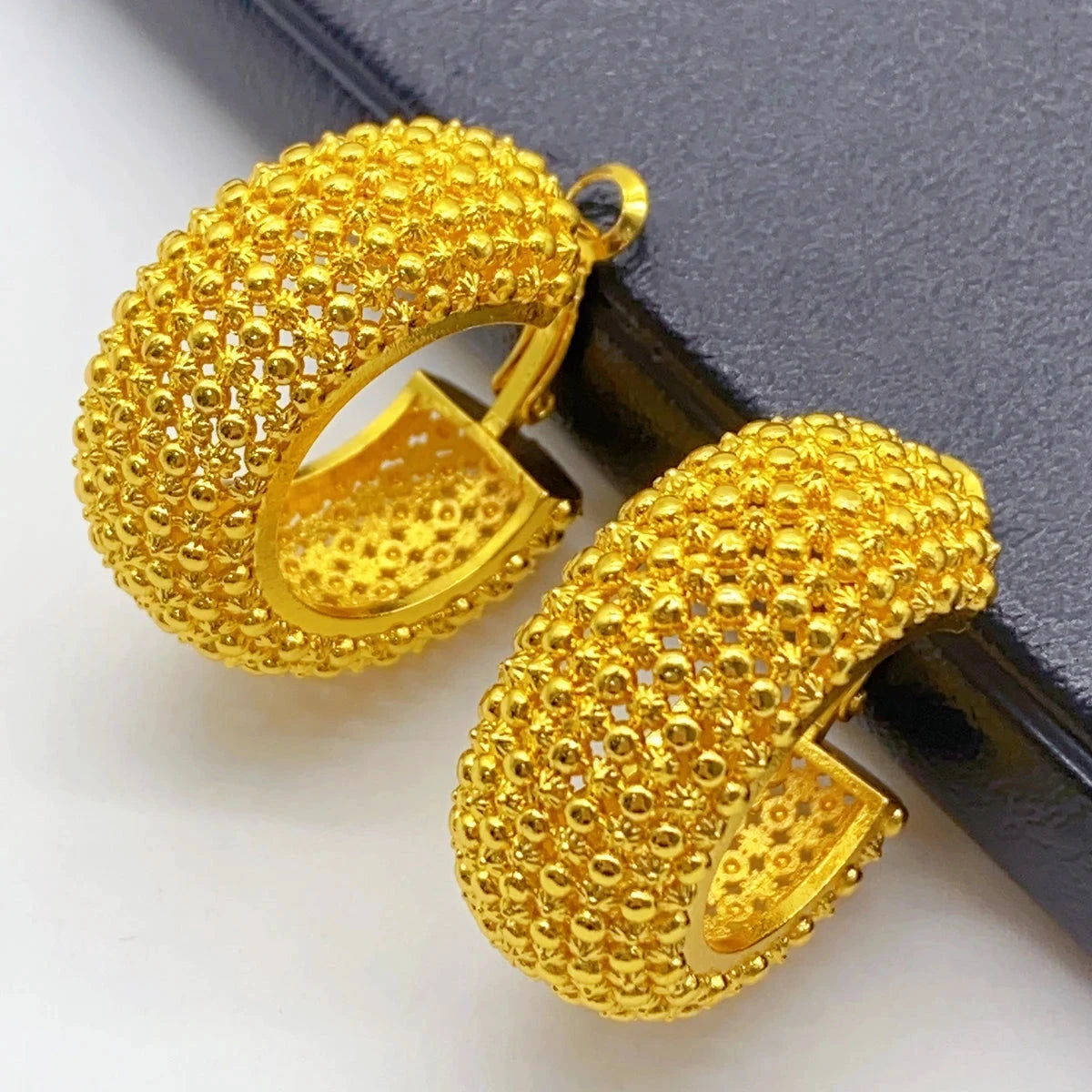 Gold hoop earrings on a black surface