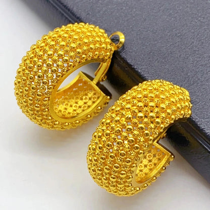 Gold hoop earrings on a black surface