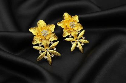 Gold floral earrings with embedded diamonds on a black background