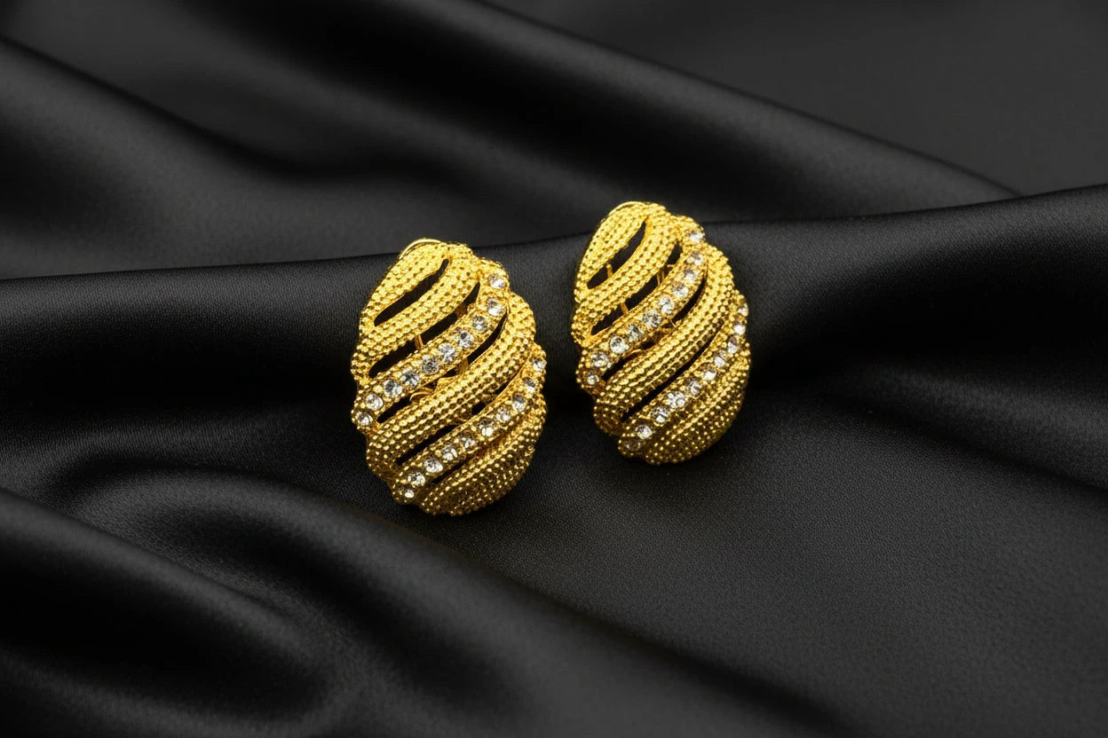 Gold earrings droplet with rhinestones on a black background