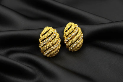 Gold earrings droplet with rhinestones on a black background