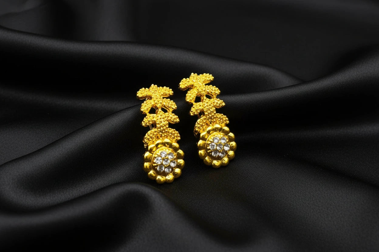 Gold earrings_flower with long leaves designs on a black surface