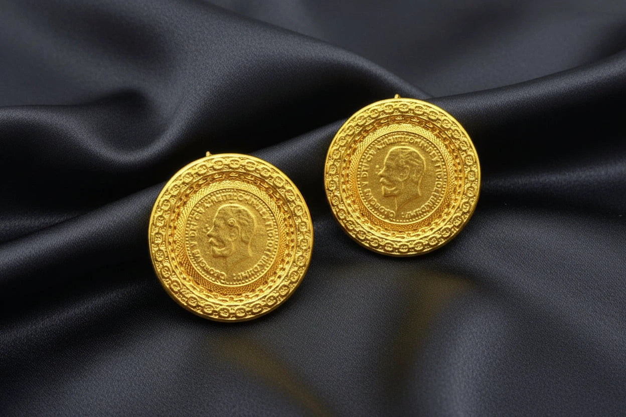 Two gold coins with embossed faces on a dark surface.